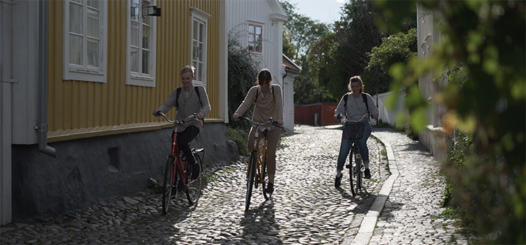 Tre studenter cyklar på kullersten i en gränd i Gamla stan i Kalmar